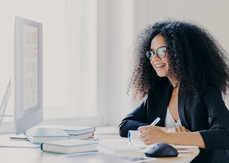 professional-curly-haired-woman-manager-makes-report-focused-into-screen-writes-down-information_t20_om6E38